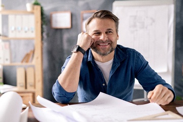 person smiling and looking over building blueprints