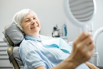 elderly woman admiring her smile with dental implants in Naples