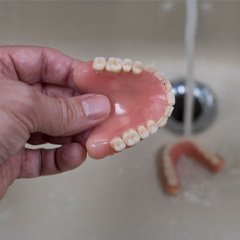 Close-up of dentures in Naples, FL being rinsed in sink