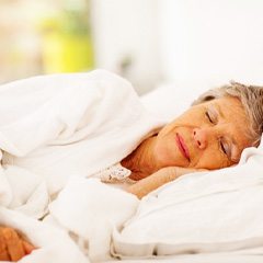 Senior woman sleeping peacefully in bed with white sheets