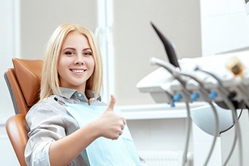 Woman giving thumbs up while in dental chair