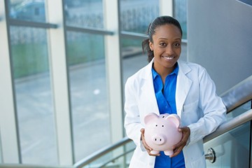 smiling dentist holding a pink piggy bank