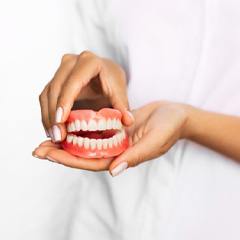 Close-up of hands holding full dentures in Naples, FL