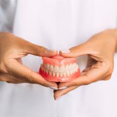 a dentist holding a pair of dentures