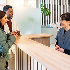 Man and woman paying for services at wooden reception counter