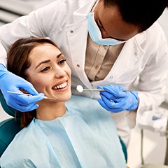 Dentist about to examine smiling woman’s mouth