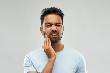 Man in blue shirt who needs an emergency dentist