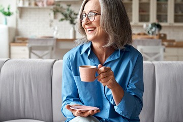 Implant dentures patient in Naples smiling with a drink