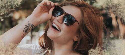 Woman with beautiful smile putting on sunglasses