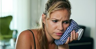 Woman holding ice pack to cheek