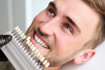 Man's smile compared with tooth shade chart