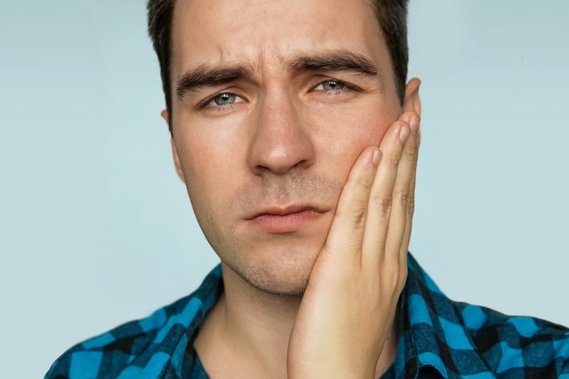 man holding cheek in pain from tooth infection