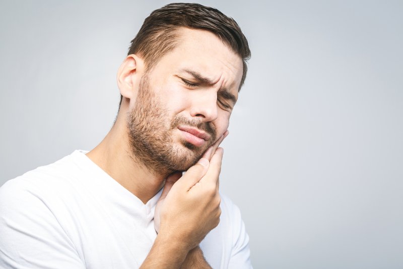 patient with infected tooth holding their cheek