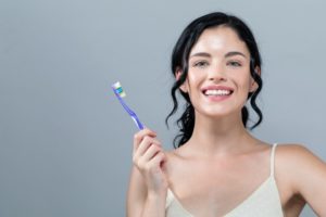 Smiling woman with toothbrush keeps healthy with tips from North Naples dentist 