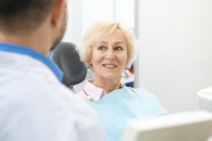 Older woman smiling in the dental chair after her dental implant surgery