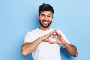 man smiling and holding his hands in the shape of a heart