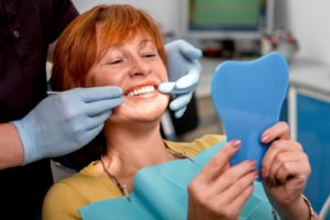 An older woman viewing her replacement teeth.