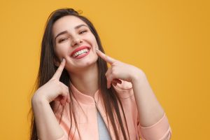 Woman pointing to her smile after getting veneers