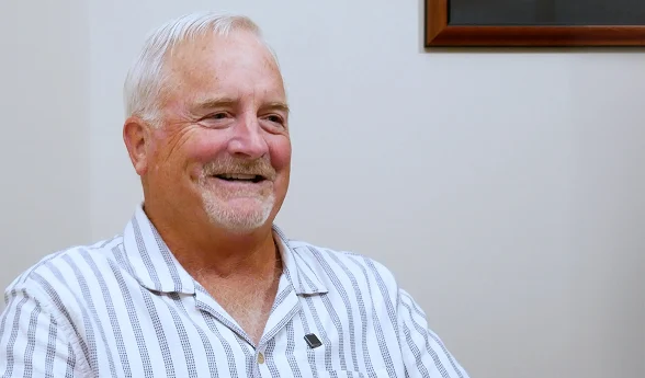 Smiling older man in a striped shirt in a patient video testimonial