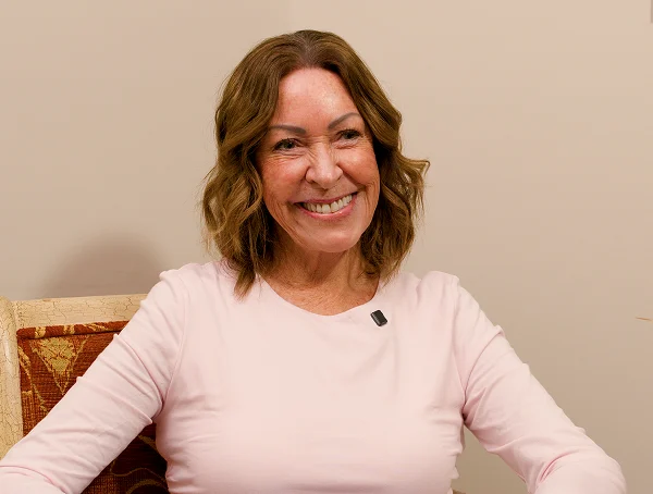 Smiling woman with brown hair wearing a light pink top