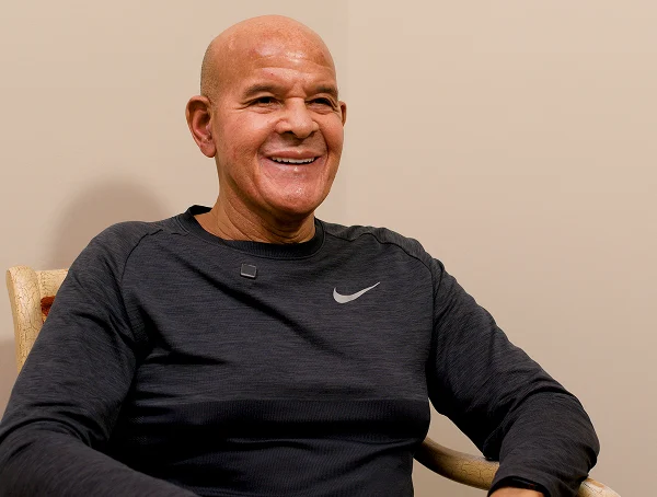 Smiling patient with a shaved head in a dark athletic shirt